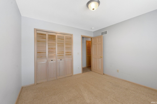 unfurnished bedroom with baseboards, visible vents, a closet, and carpet