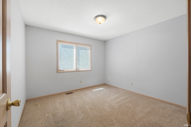 unfurnished room featuring baseboards, visible vents, a textured ceiling, and carpet