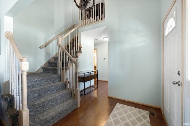 foyer entrance featuring baseboards, visible vents, wood finished floors, and stairs