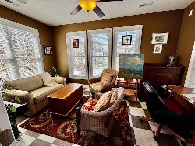 living area featuring ceiling fan, tile patterned floors, and visible vents