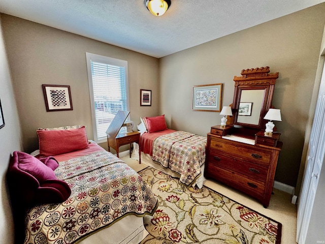 bedroom with light carpet, a textured ceiling, and baseboards