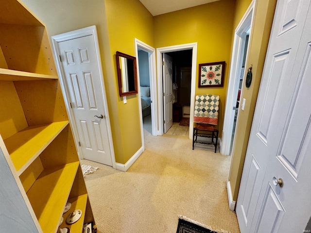 hall featuring light carpet and baseboards