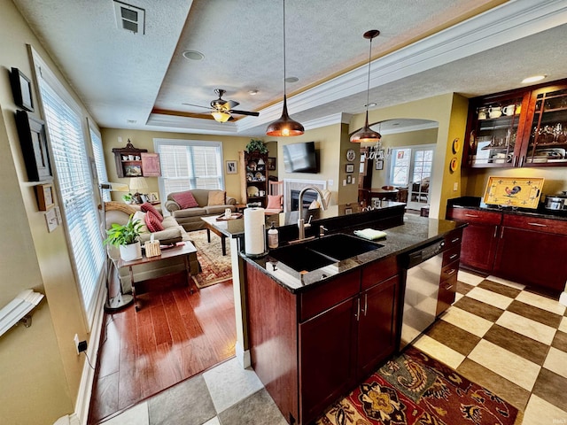 kitchen with stainless steel dishwasher, a tray ceiling, a textured ceiling, a sink, and reddish brown cabinets