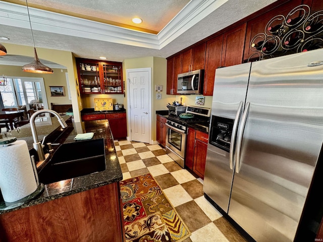 kitchen with stainless steel appliances, a sink, a textured ceiling, light floors, and a raised ceiling