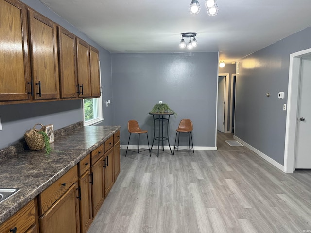 15336 County Farm Rd, Shoals, IN 47581 - kitchen featuring brown cabinetry, dark countertops, light wood finished floors, and baseboards