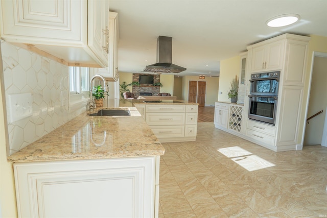 5793 E Pierce Rd, Monticello, IN 47960 - kitchen with island exhaust hood, light stone counters, a peninsula, double oven, and a sink
