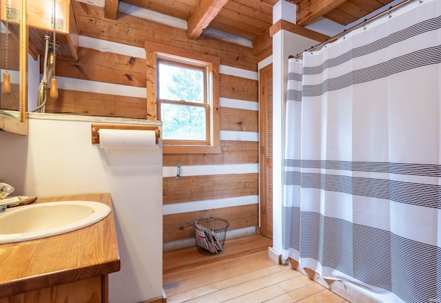 full bathroom with curtained shower, wooden walls, hardwood / wood-style floors, beamed ceiling, and wooden ceiling