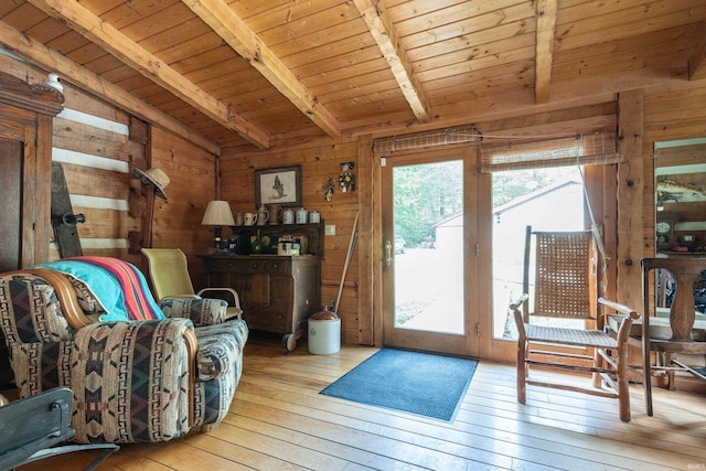 sitting room with wooden walls, vaulted ceiling with beams, wooden ceiling, and hardwood / wood-style flooring
