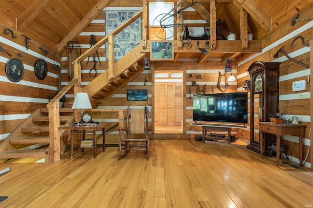 living room with wooden walls, stairs, beam ceiling, wood-type flooring, and wood ceiling