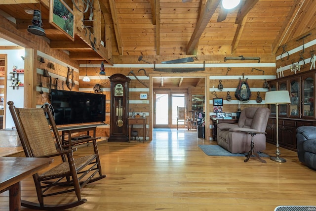 living area with ceiling fan, lofted ceiling with beams, wood ceiling, wood finished floors, and wood walls