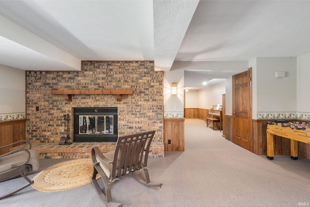 living room with carpet flooring, wood walls, a wainscoted wall, and a fireplace