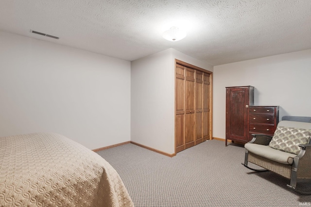 carpeted bedroom with baseboards, a textured ceiling, visible vents, and a closet
