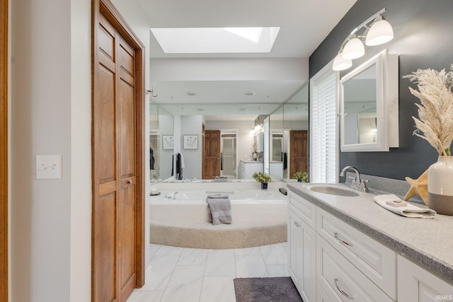 bathroom with marble finish floor, vanity, a closet, a skylight, and a garden tub