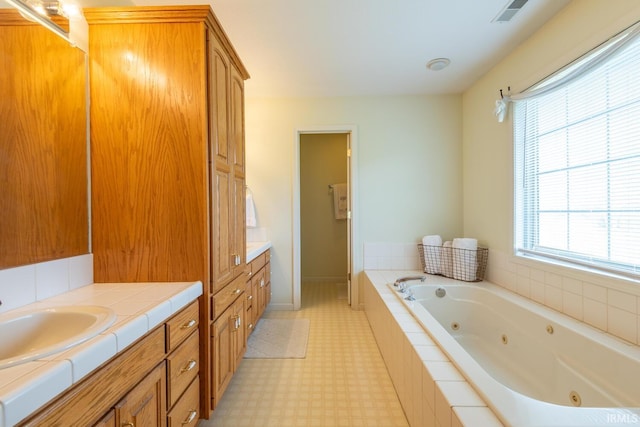 full bathroom featuring tile patterned floors, vanity, a tub with jets, and visible vents