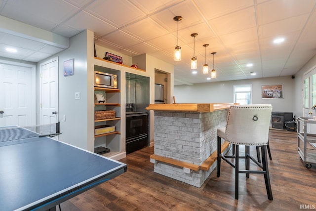 bar featuring stainless steel microwave, dark wood-style flooring, black / electric stove, decorative light fixtures, and indoor bar