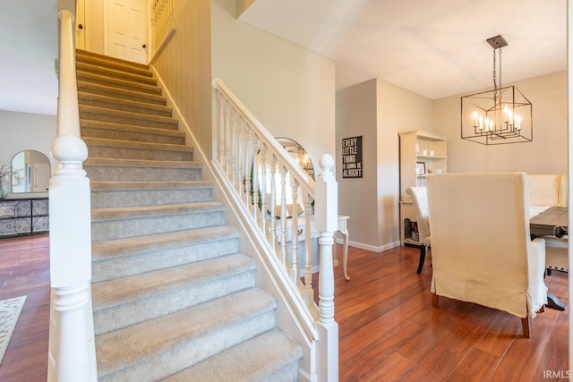 stairs with wood finished floors, an inviting chandelier, and baseboards