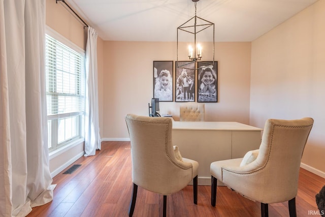 dining area featuring wood finished floors, an inviting chandelier, baseboards, and visible vents