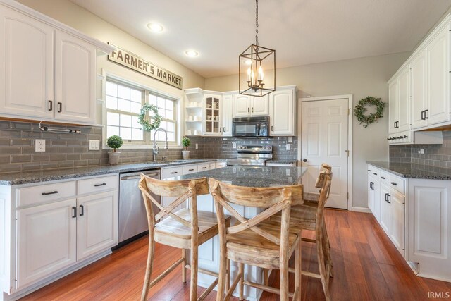 kitchen featuring dark wood finished floors, a kitchen breakfast bar, white cabinetry, appliances with stainless steel finishes, and a sink