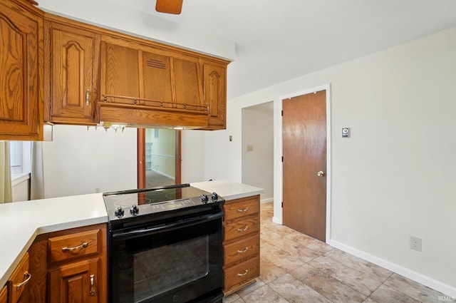 kitchen featuring brown cabinetry, black electric range, light countertops, and baseboards