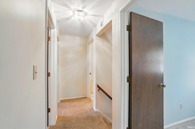 hallway with baseboards, an upstairs landing, and light colored carpet
