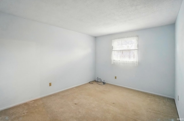 unfurnished room with baseboards, light colored carpet, and a textured ceiling
