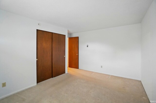 unfurnished bedroom with light carpet and a closet