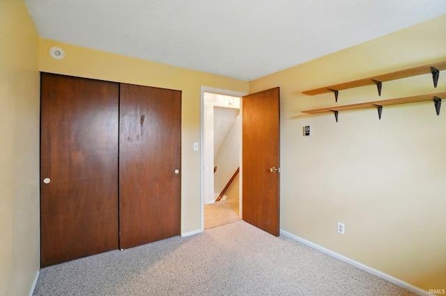 unfurnished bedroom with carpet, a closet, and baseboards