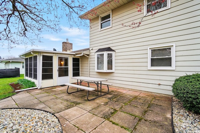 back of house with a patio, a sunroom, and a chimney