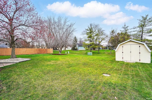 view of yard with an outbuilding, a storage unit, and fence