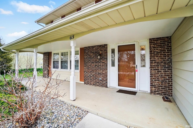 property entrance featuring brick siding and a porch