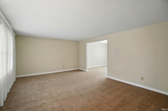 carpeted spare room featuring baseboards