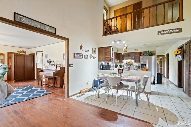 dining room featuring a wealth of natural light, a high ceiling, light wood-style floors, and baseboards