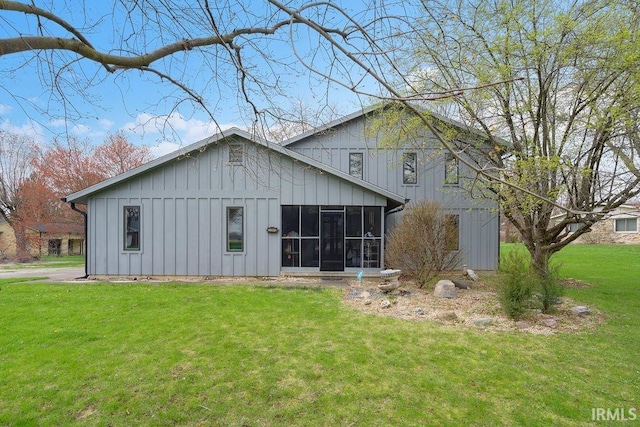 rear view of property featuring a sunroom, board and batten siding, and a yard