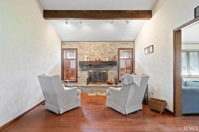 living area featuring rail lighting, a wealth of natural light, a fireplace, and wood finished floors