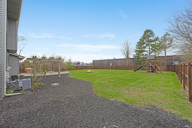 view of yard with a playground, central AC, and a fenced backyard