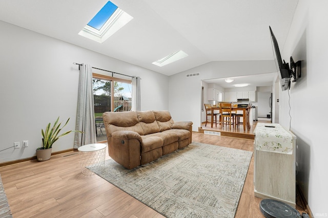living area with visible vents, light wood finished floors, and vaulted ceiling with skylight