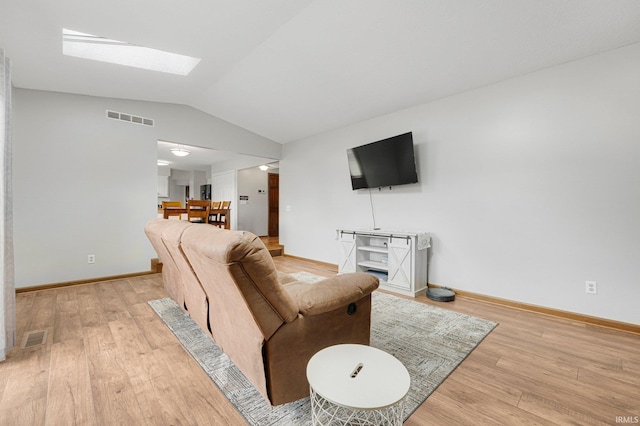 living room featuring baseboards, visible vents, light wood-type flooring, and vaulted ceiling with skylight