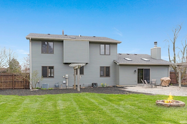 back of property featuring a chimney, an outdoor fire pit, fence, and a lawn