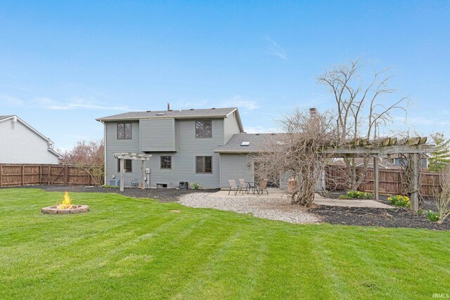 rear view of house with a patio, a fire pit, a fenced backyard, and a lawn