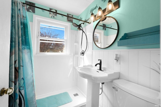 full bathroom with a wainscoted wall, a shower with curtain, and toilet