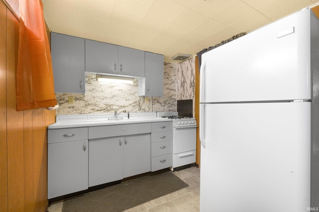 kitchen featuring white appliances, light countertops, a sink, and gray cabinets