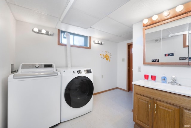 washroom with laundry area, light floors, a sink, baseboards, and washing machine and dryer