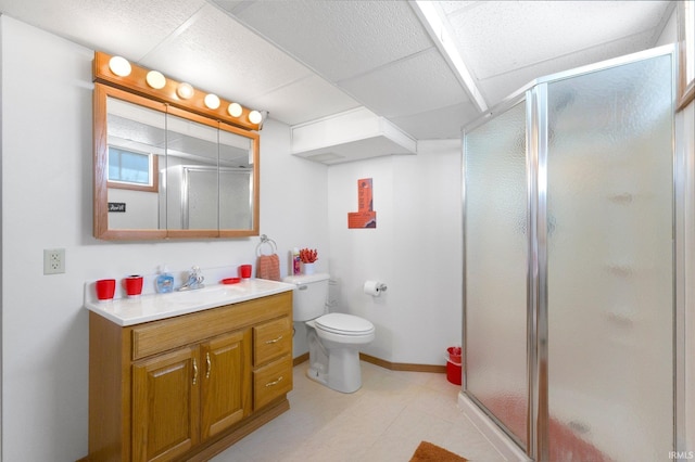 bathroom with a shower stall, vanity, baseboards, and toilet