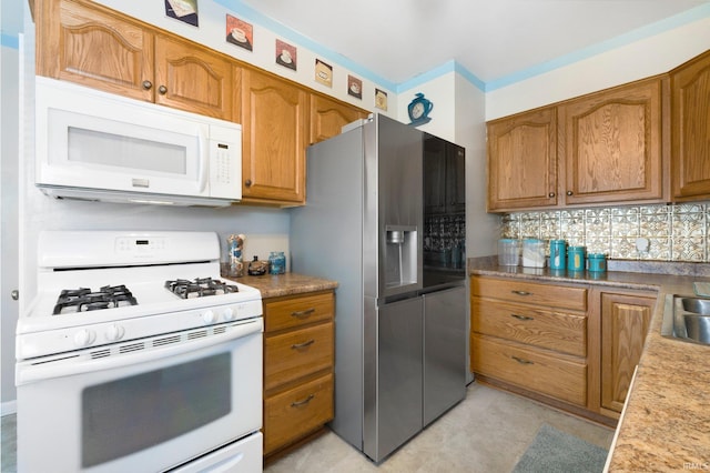kitchen featuring brown cabinets, decorative backsplash, white appliances, and a sink