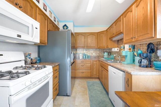 kitchen featuring tasteful backsplash, white appliances, light countertops, ceiling fan, and a sink