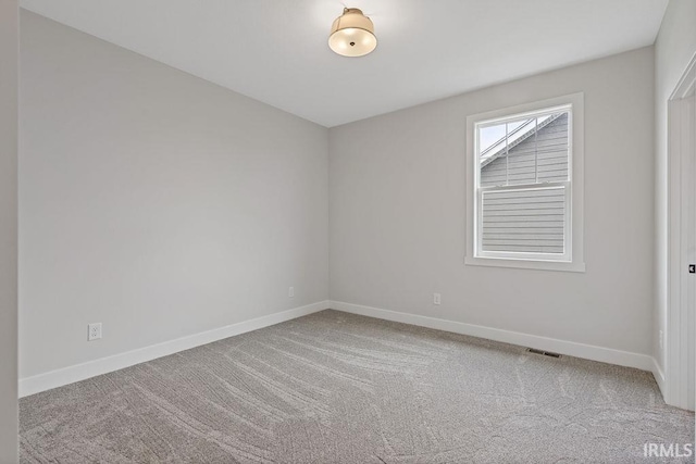 spare room featuring carpet floors, baseboards, and visible vents