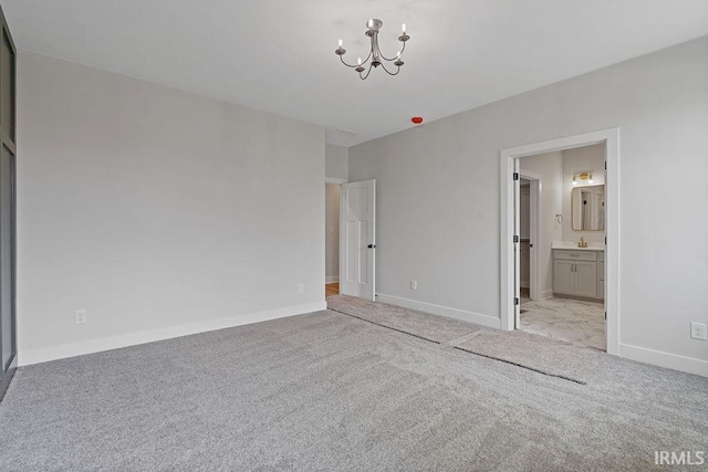 unfurnished bedroom featuring a chandelier, ensuite bathroom, baseboards, and carpet
