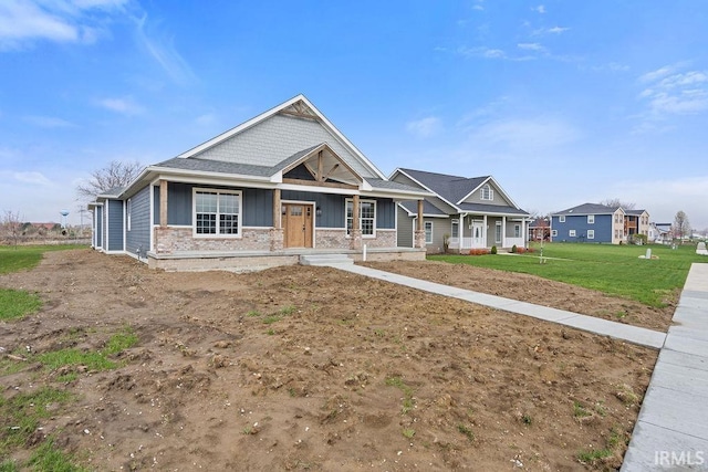 craftsman-style house featuring board and batten siding, a front lawn, brick siding, and covered porch