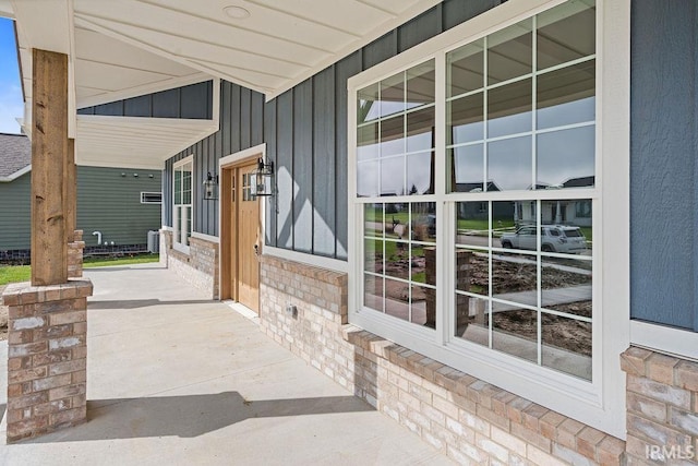 entrance to property with brick siding, covered porch, and board and batten siding