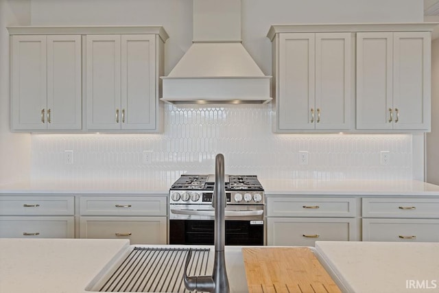 kitchen featuring custom range hood, range with two ovens, and decorative backsplash